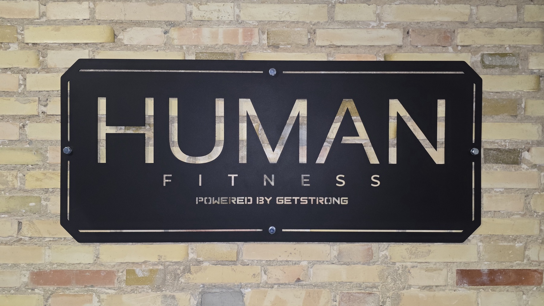 Cartel de HUMAN FITNESS sobre pared de ladrillo