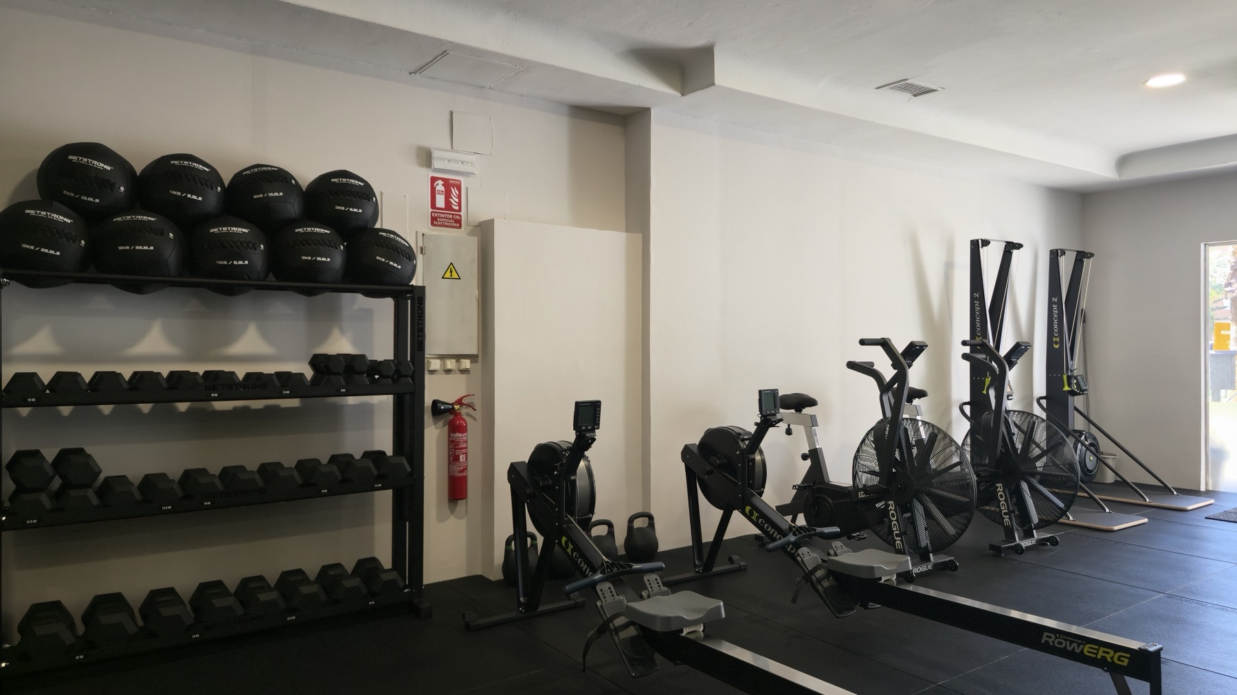 Zona de cardio con remos, bicis y mancuernas
